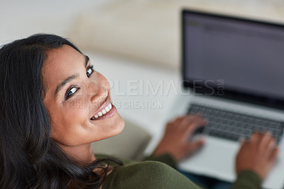 Buy stock photo Portrait of an attractive young woman using her laptop while sitting on the sofa at home