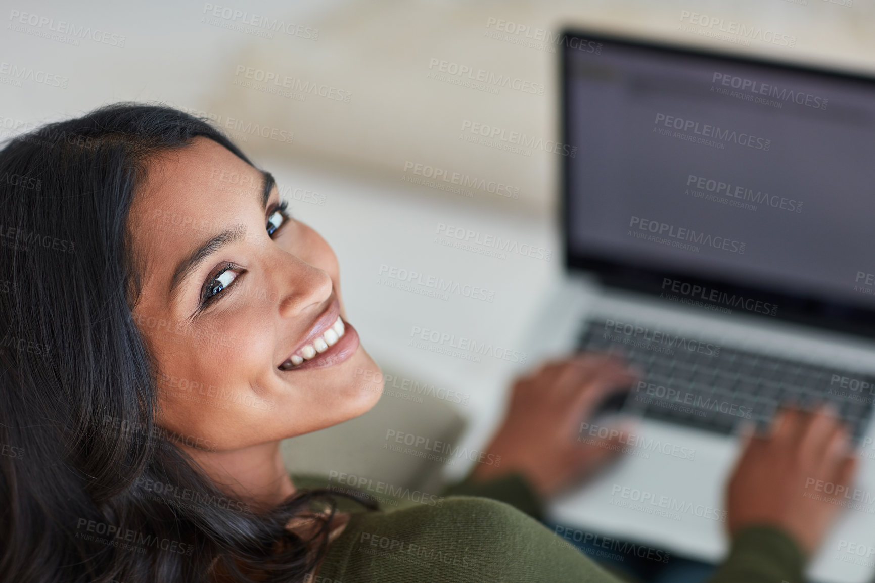 Buy stock photo Portrait of an attractive young woman using her laptop while sitting on the sofa at home