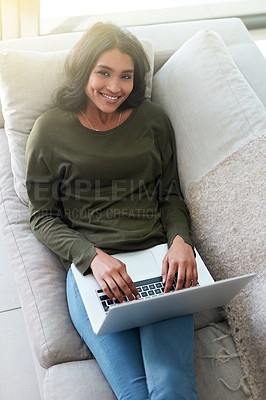 Buy stock photo Portrait of an attractive young woman using her laptop while relaxing on the sofa at home