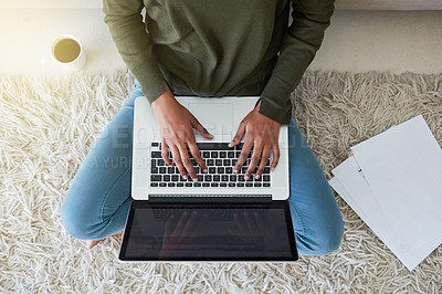 Buy stock photo Shot of an unrecognizable young woman using her laptop while sitting on the living room floor