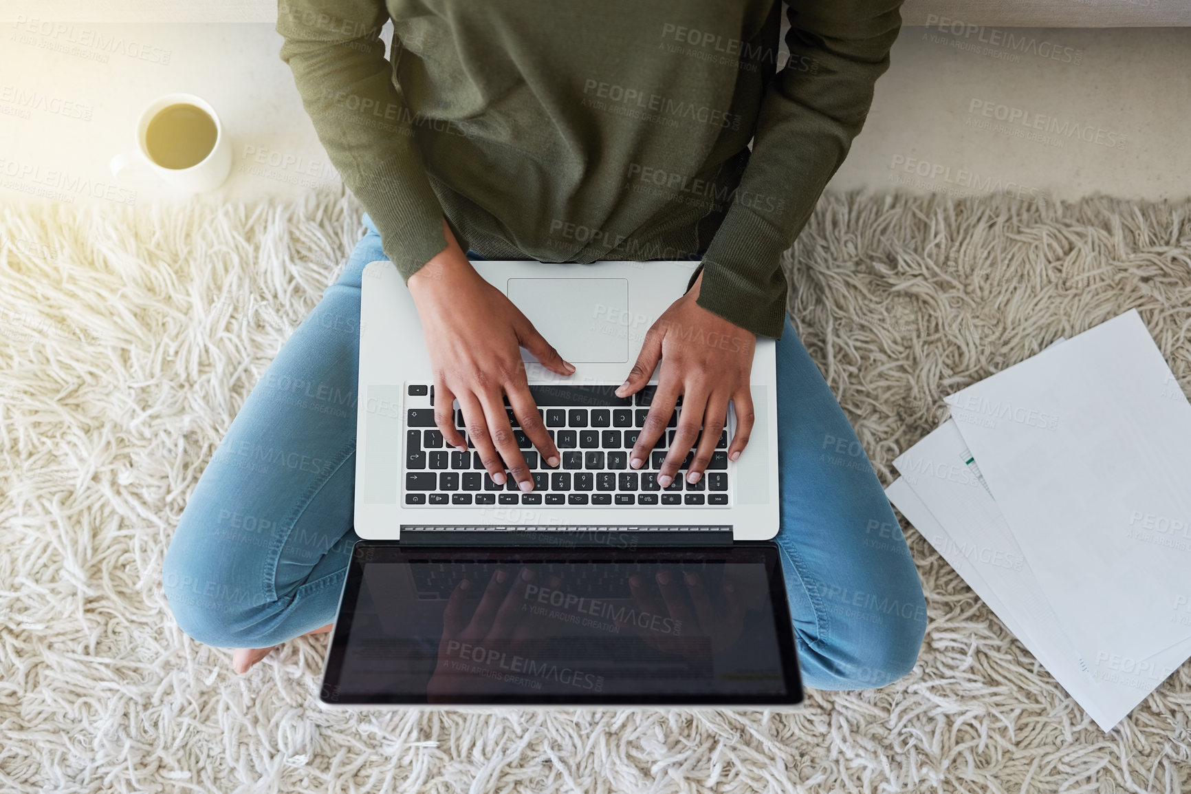 Buy stock photo Shot of an unrecognizable young woman using her laptop while sitting on the living room floor