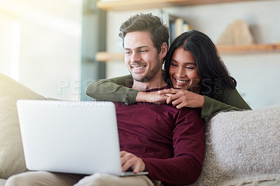 Buy stock photo Shot of an affectionate young couple using their laptop while relaxing on the sofa at home