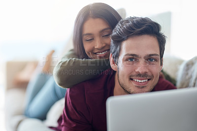Buy stock photo Shot of an affectionate young couple using their laptop while lying on the sofa at home