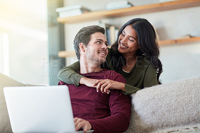 Buy stock photo Shot of an affectionate young couple using their laptop while relaxing on the sofa at home