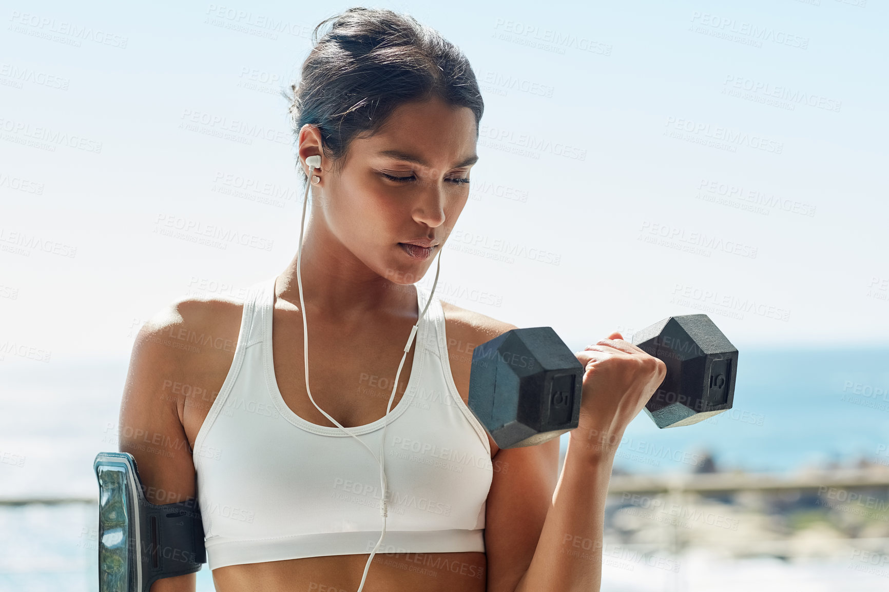 Buy stock photo Indian girl, earphones and dumbbell for fitness in outdoor, bicep and training for muscle growth. Female person, confident and music for weight lifting, strong body and workout for power or health