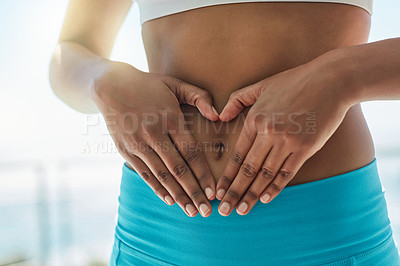 Buy stock photo Cropped shot of a healthy woman forming a heart shape over her stomach