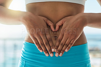 Buy stock photo Cropped shot of a healthy woman forming a heart shape over her stomach