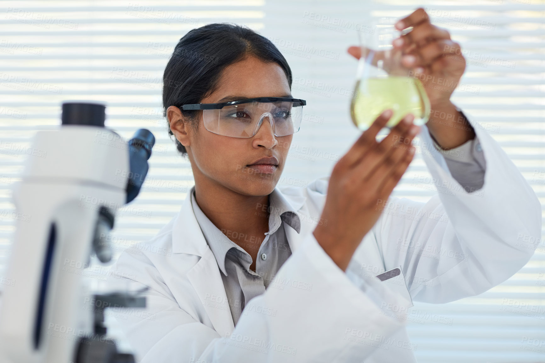 Buy stock photo Cropped shot of a young female scientist conducting an experiment in a lab