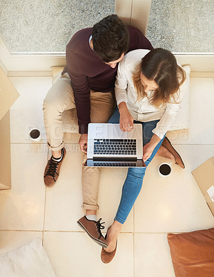 Buy stock photo High angle shot of a young couple using a laptop while moving into a new home