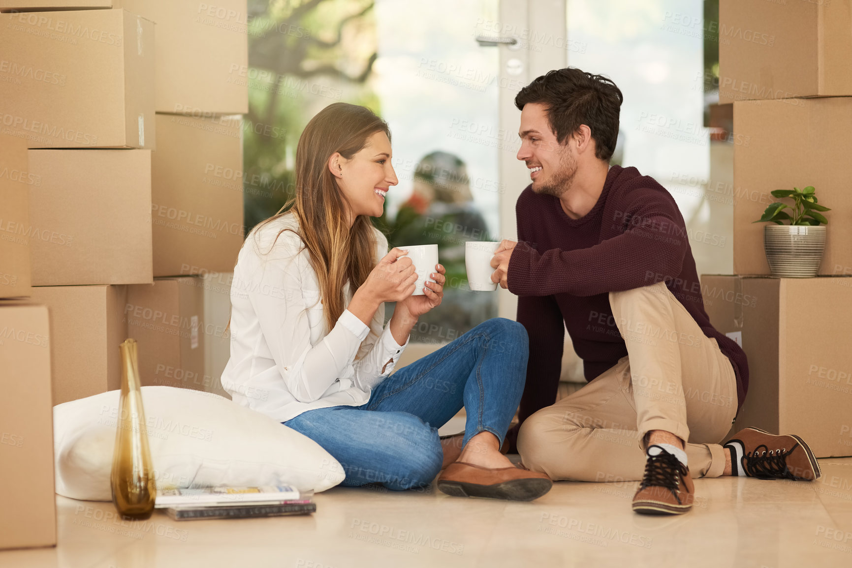 Buy stock photo Shot of an affectionate young couple taking a coffee break while moving into a new home
