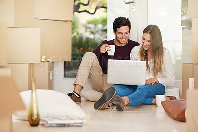 Buy stock photo Shot of a young couple using a laptop while moving into a new home