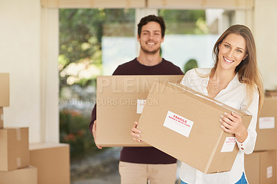 Buy stock photo Portrait of a smiling young couple carrying boxes while moving into their new home