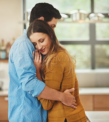 Buy stock photo Shot of an affectionate young couple embracing in their kitchen