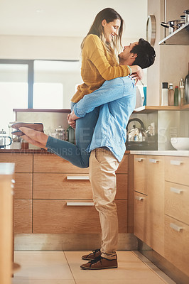 Buy stock photo Shot of an affectionate young couple embracing in their kitchen