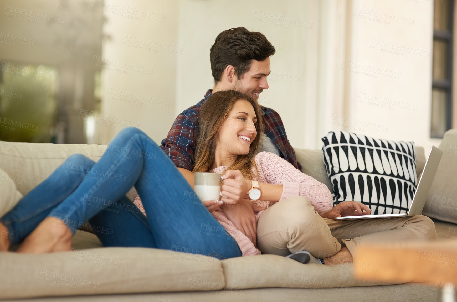 Buy stock photo Shot of a happy young couple using a laptop together while relaxing on the   sofa at home