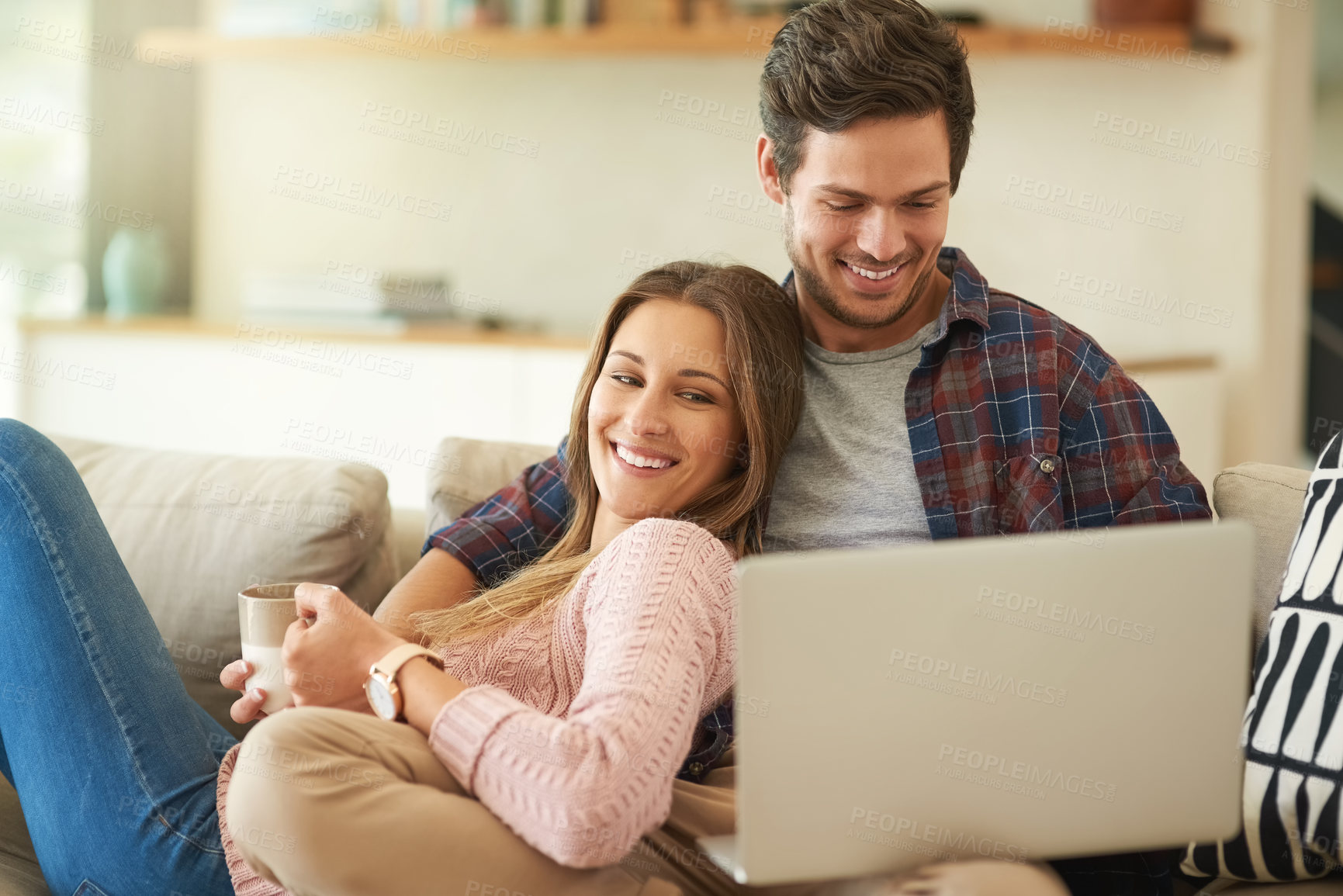 Buy stock photo Shot of a happy young couple using a laptop together while relaxing on the   sofa at home