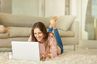 Buy stock photo Shot of an attractive young woman using her laptop while relaxing in her lounge at home