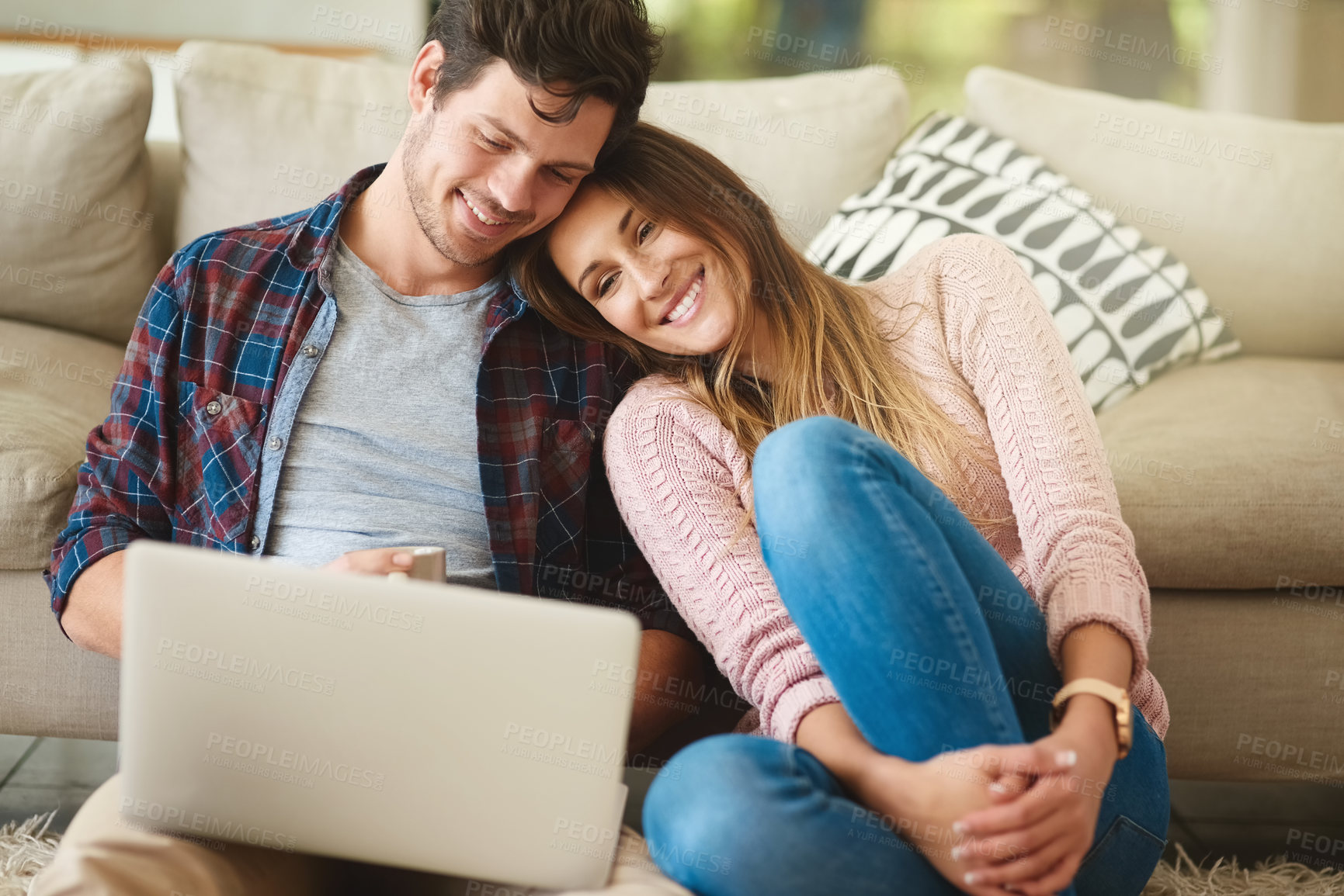 Buy stock photo Shot of a happy young couple using a laptop together while relaxing in their lounge at home