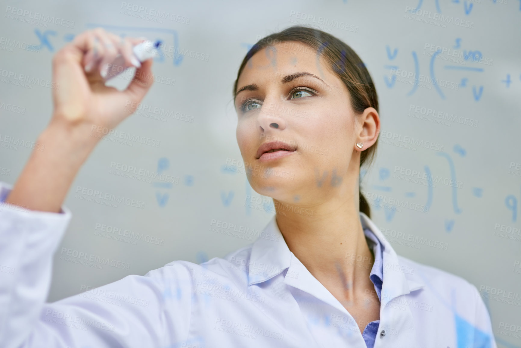 Buy stock photo Cropped shot of a young female scientist writing equations on a glass wall in a lab