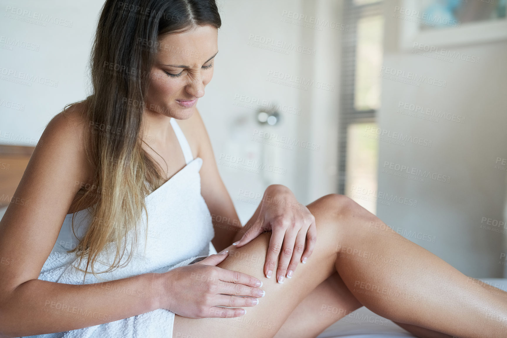 Buy stock photo Shot of a young woman looking unimpressed while pinching the skin on her thigh in her bedroom at home