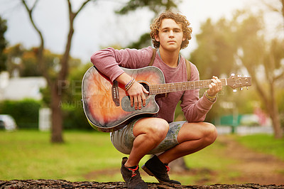 Buy stock photo Portrait of a young man playing guitar outside