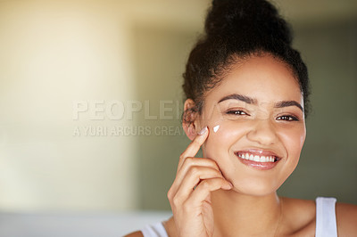 Buy stock photo Portrait of an attractive young woman applying moisturizer to her face