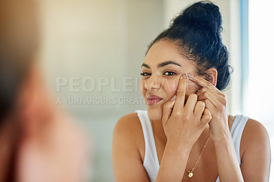 Buy stock photo Shot of a young woman squeezing a pimple in front of the bathroom mirror