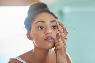 Buy stock photo Shot of an attractive young woman putting in her contact lenses at home