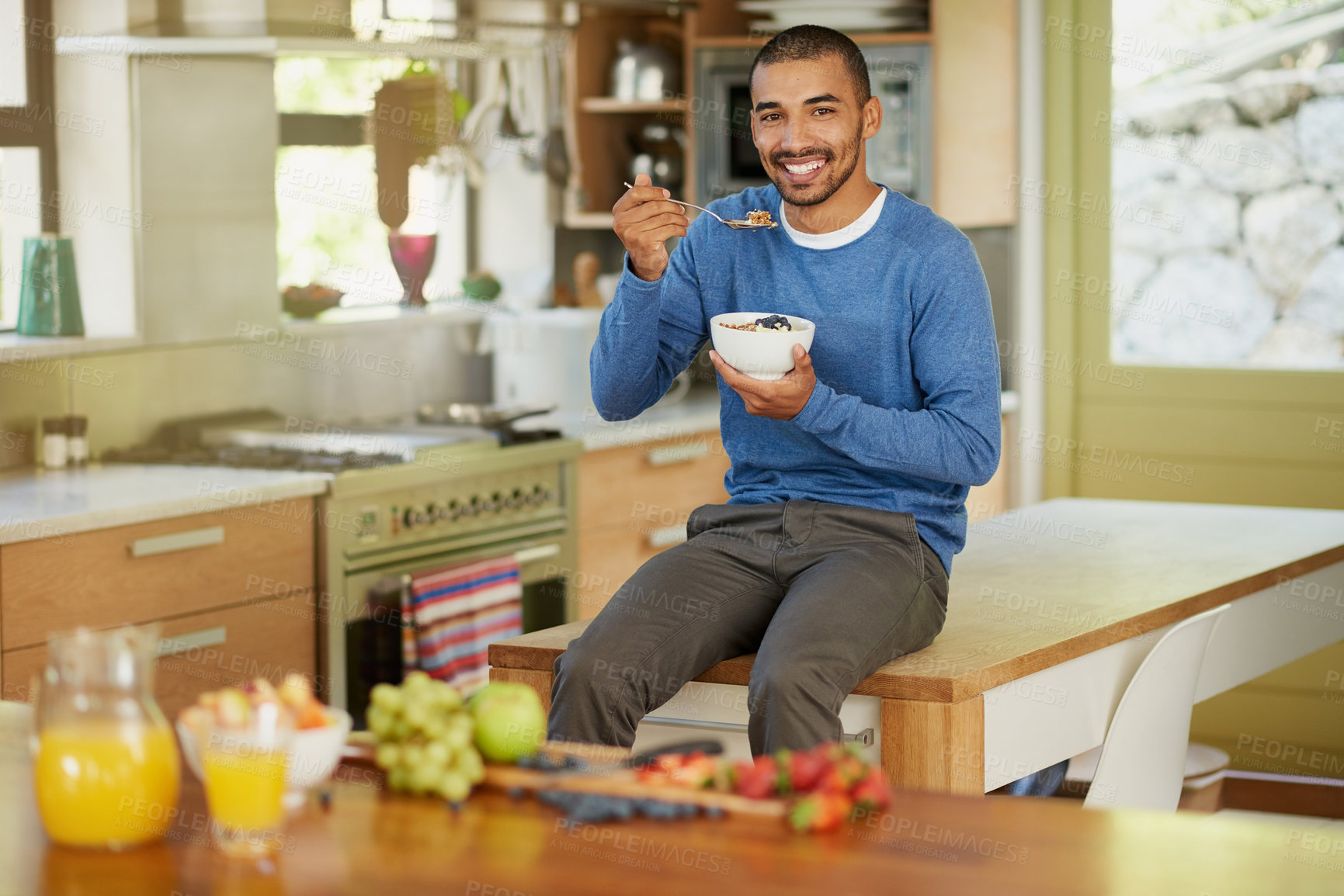 Buy stock photo Portrait of a happy young man enjoying a bowl of muesli at home