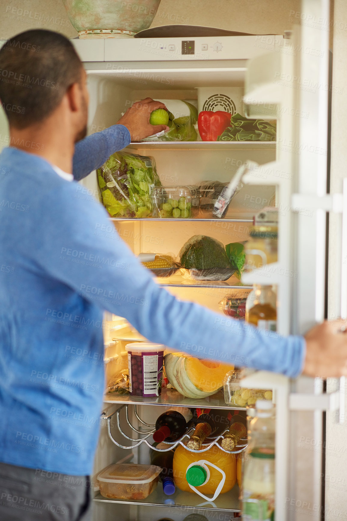 Buy stock photo Rearview shot of a man opening a fridge filled with healthy food at home