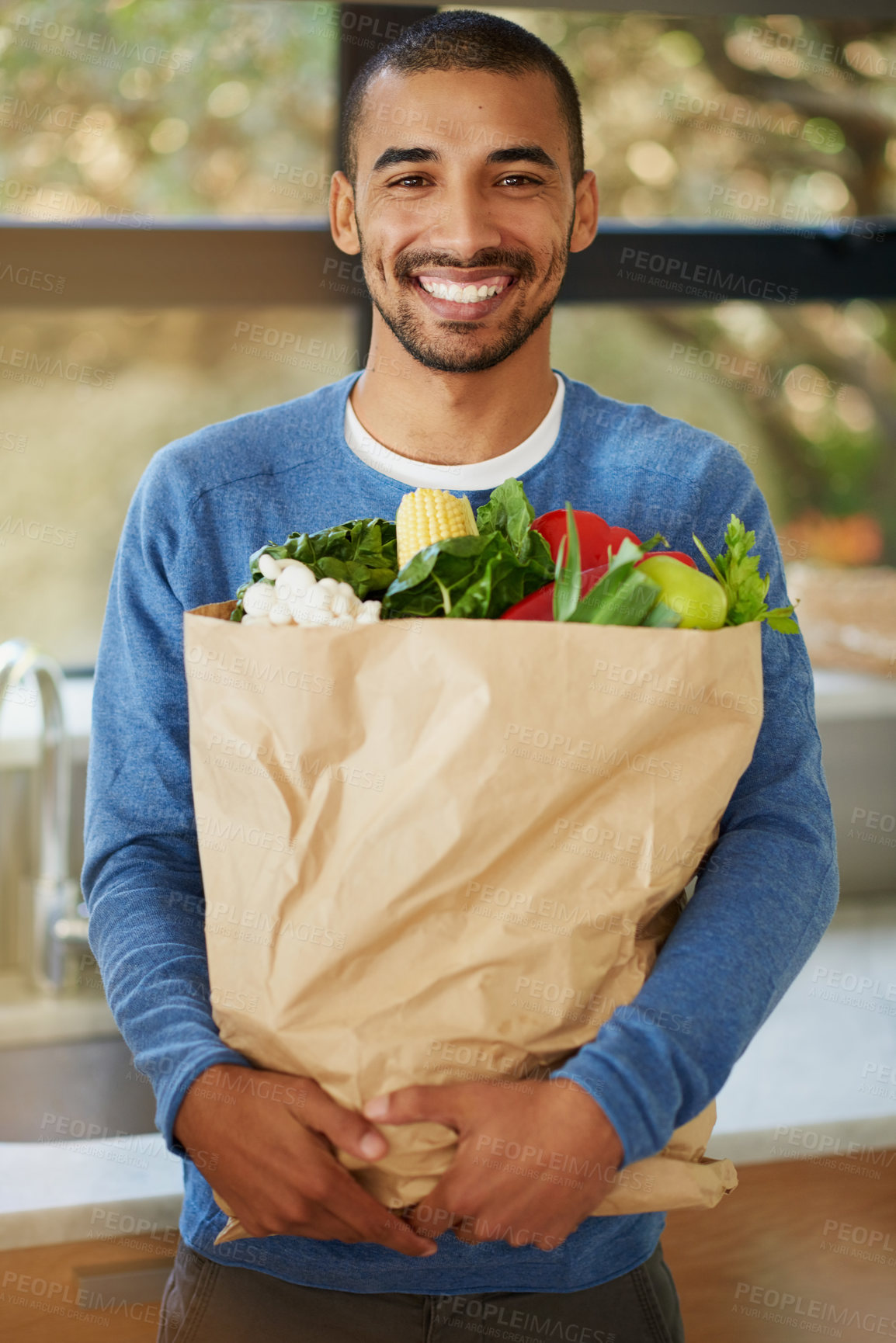 Buy stock photo Portrait of a happy young man holding a bag full of healthy vegetables at home