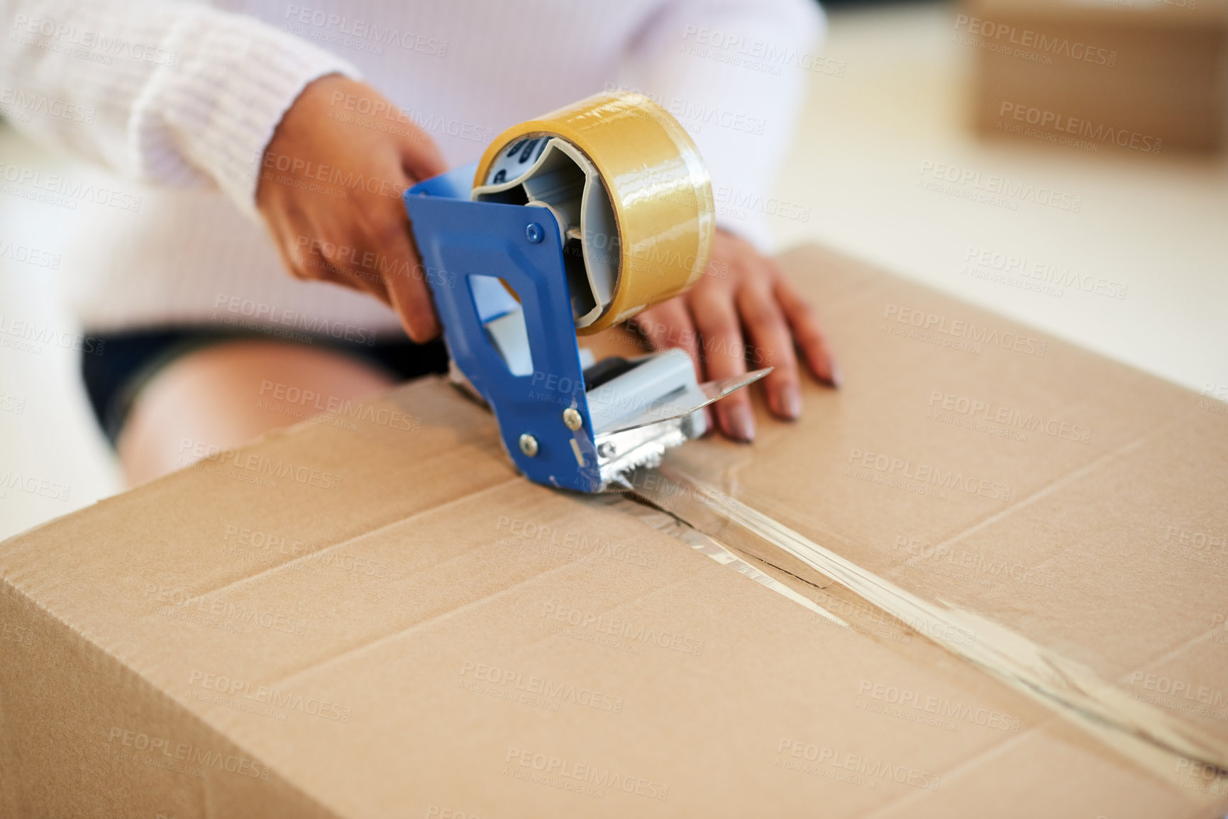 Buy stock photo Shot of an unidentifiable young woman packing boxes while moving house