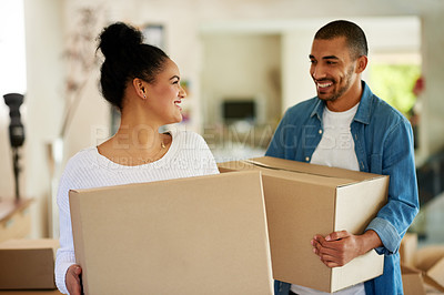 Buy stock photo Shot of a happy young couple carrying cardboard boxes into their new home