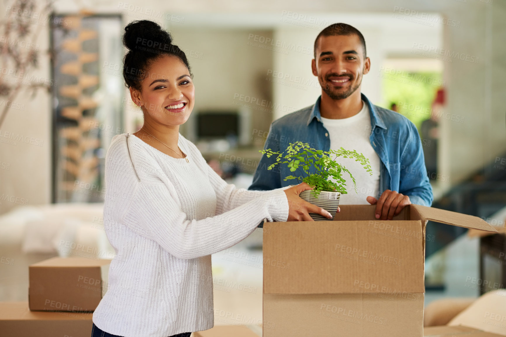 Buy stock photo Portrait of a happy young couple unpacking boxes in their new home together
