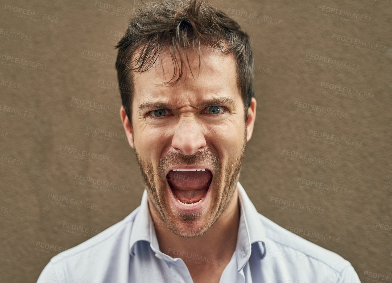 Buy stock photo Portrait of an angry young man standing against a dark background