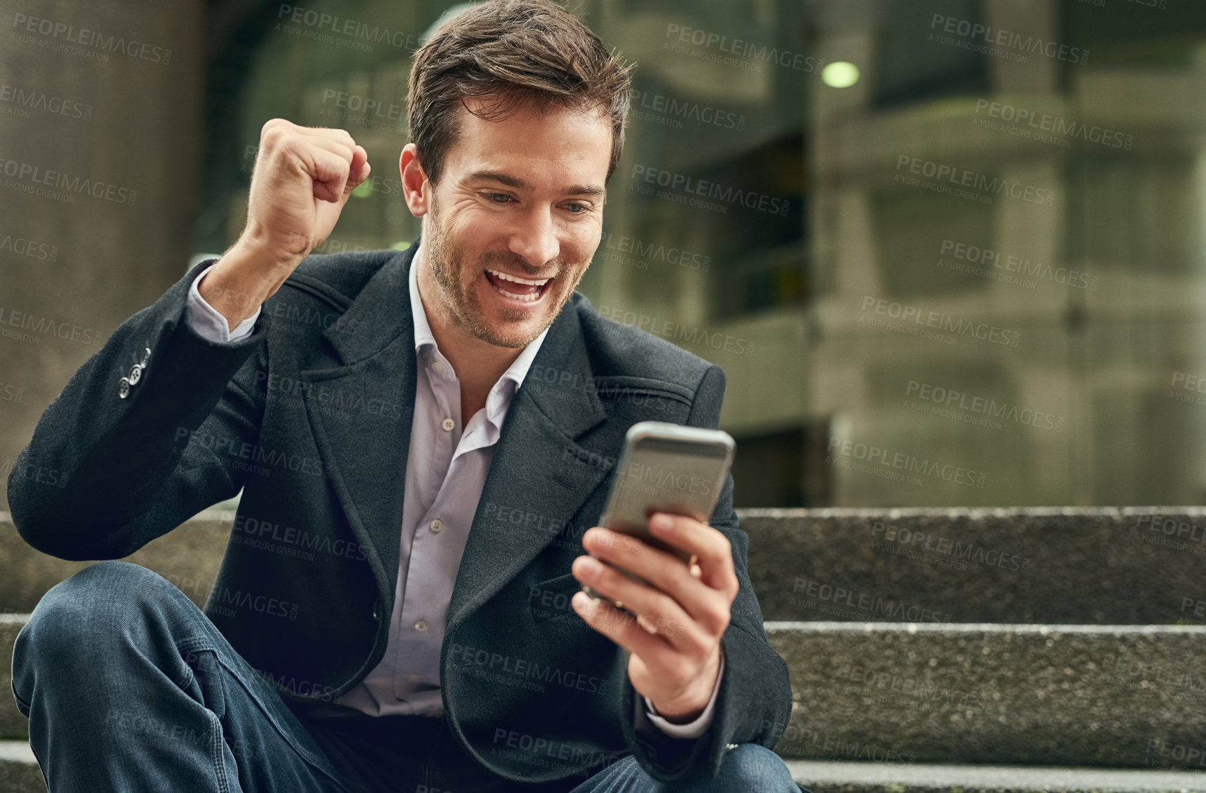Buy stock photo Cropped shot of a young businessman making a fist pump while looking at his cellphone