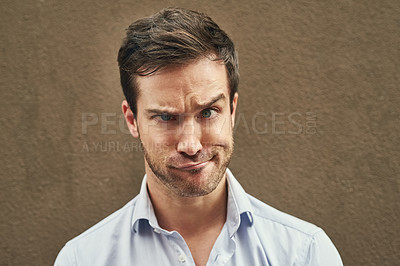 Buy stock photo Portrait of a young man pulling a funny face against a dark background