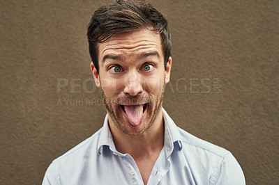 Buy stock photo Portrait of a young man pulling a funny face against a dark background