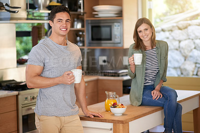 Buy stock photo Portrait of a happy young couple drinking coffee in their kitchen together