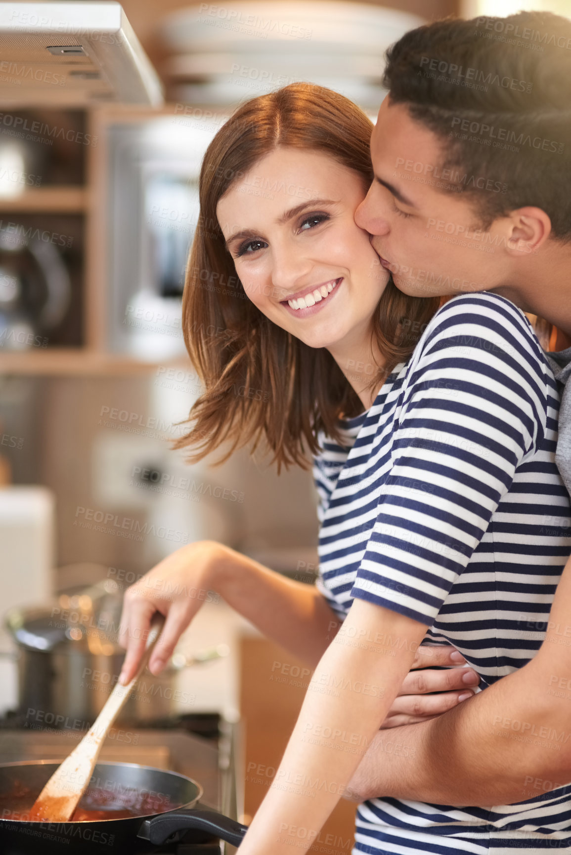 Buy stock photo Portrait of an affectionate young couple cooking a meal together in their kitchen