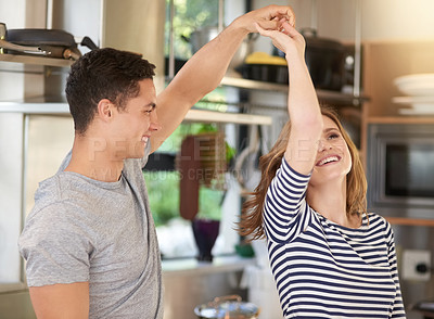 Buy stock photo Shot of a happy young couple dancing in their kitchen at home