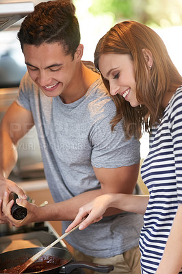 Buy stock photo Shot of a happy young couple cooking a meal together in their kitchen