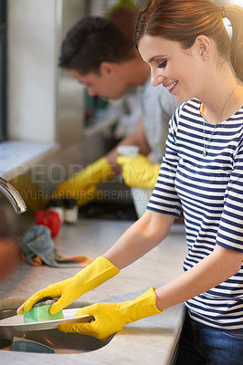 Buy stock photo Shot of a happy young couple cleaning their kitchen together
