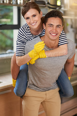 Buy stock photo Portrait of happy young man giving his wife a piggyback ride while they clean their kitchen