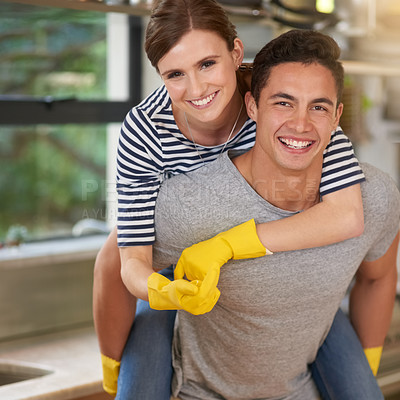 Buy stock photo Portrait of happy young man giving his wife a piggyback ride while they clean their kitchen