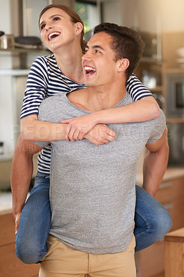 Buy stock photo Shot of a happy young couple enjoying a lighthearted moment in their kitchen at home