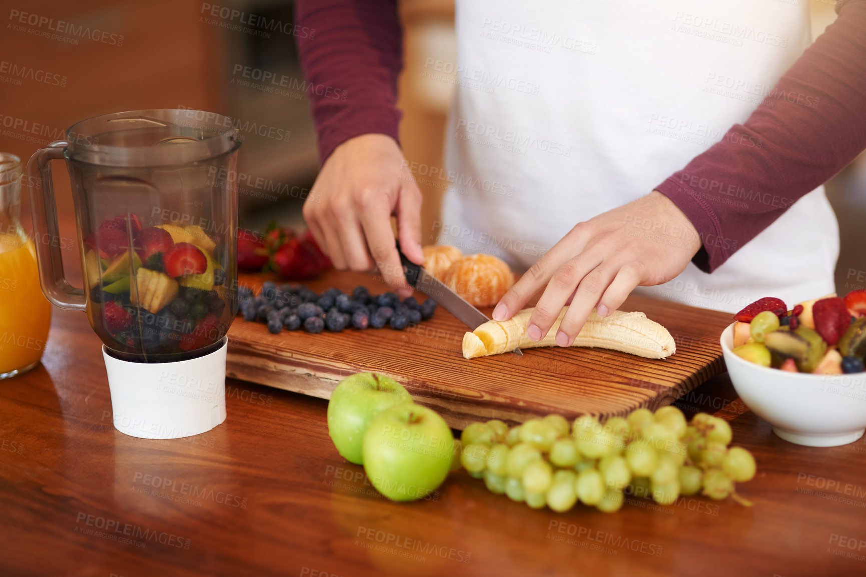 Buy stock photo Hands, fruit and prepare with blender on chopping board in kitchen for health or wellness with nutrition. Person, knife and cutting banana for tropical salad with organic food in home for fiber.