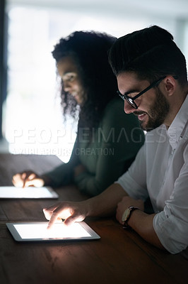 Buy stock photo Cropped shot of two colleagues working late on their digital tablets in an office