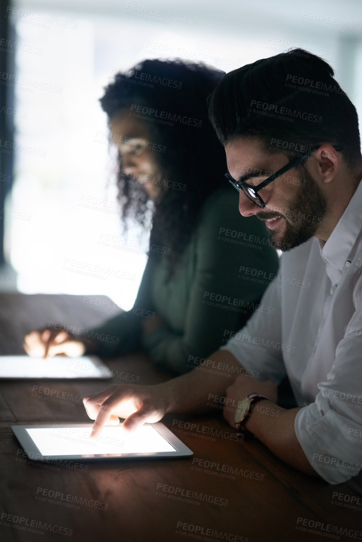 Buy stock photo Cropped shot of two colleagues working late on their digital tablets in an office