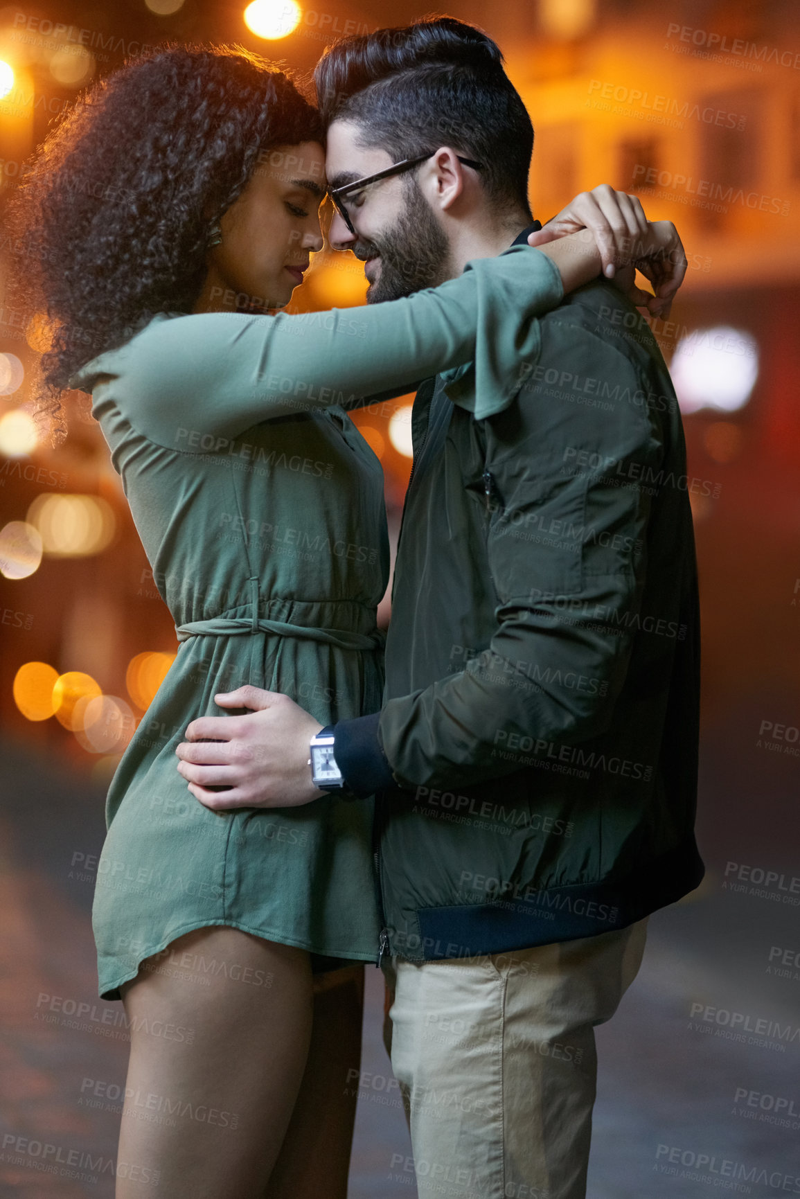 Buy stock photo Shot of a happy young couple embracing outdoors at night